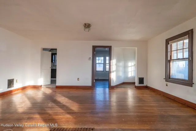 a view of an empty room with window and wooden floor