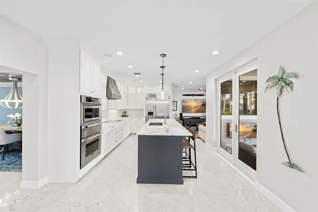 a kitchen with stainless steel appliances kitchen island granite countertop a sink a refrigerator and chairs