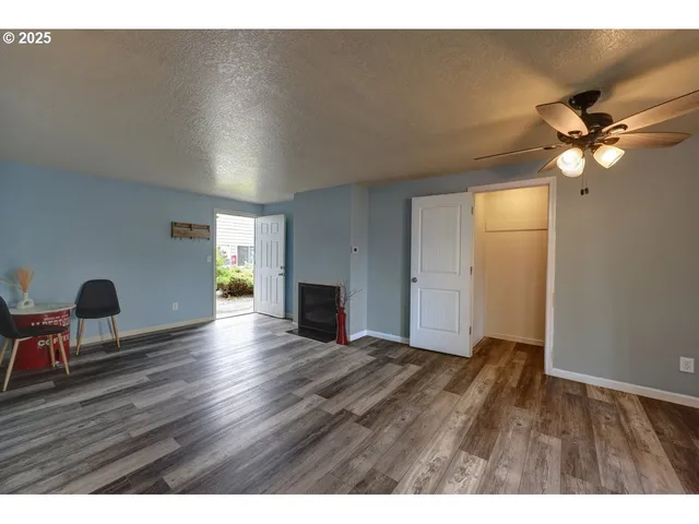 a view of an empty room with window and wooden floor