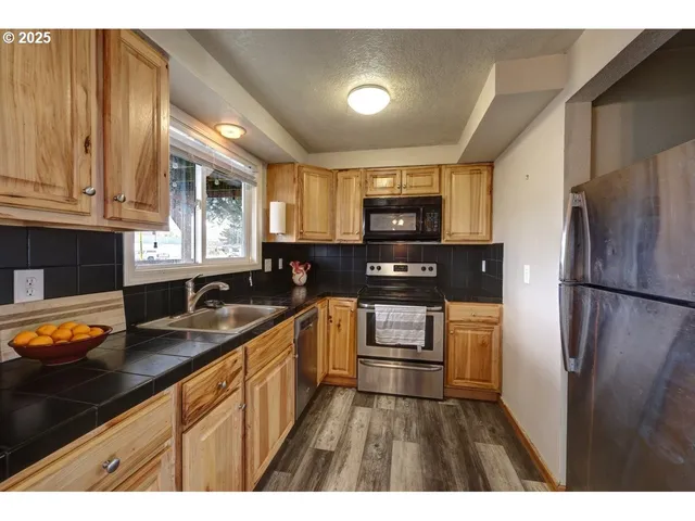 a kitchen with granite countertop stainless steel appliances a refrigerator sink and microwave