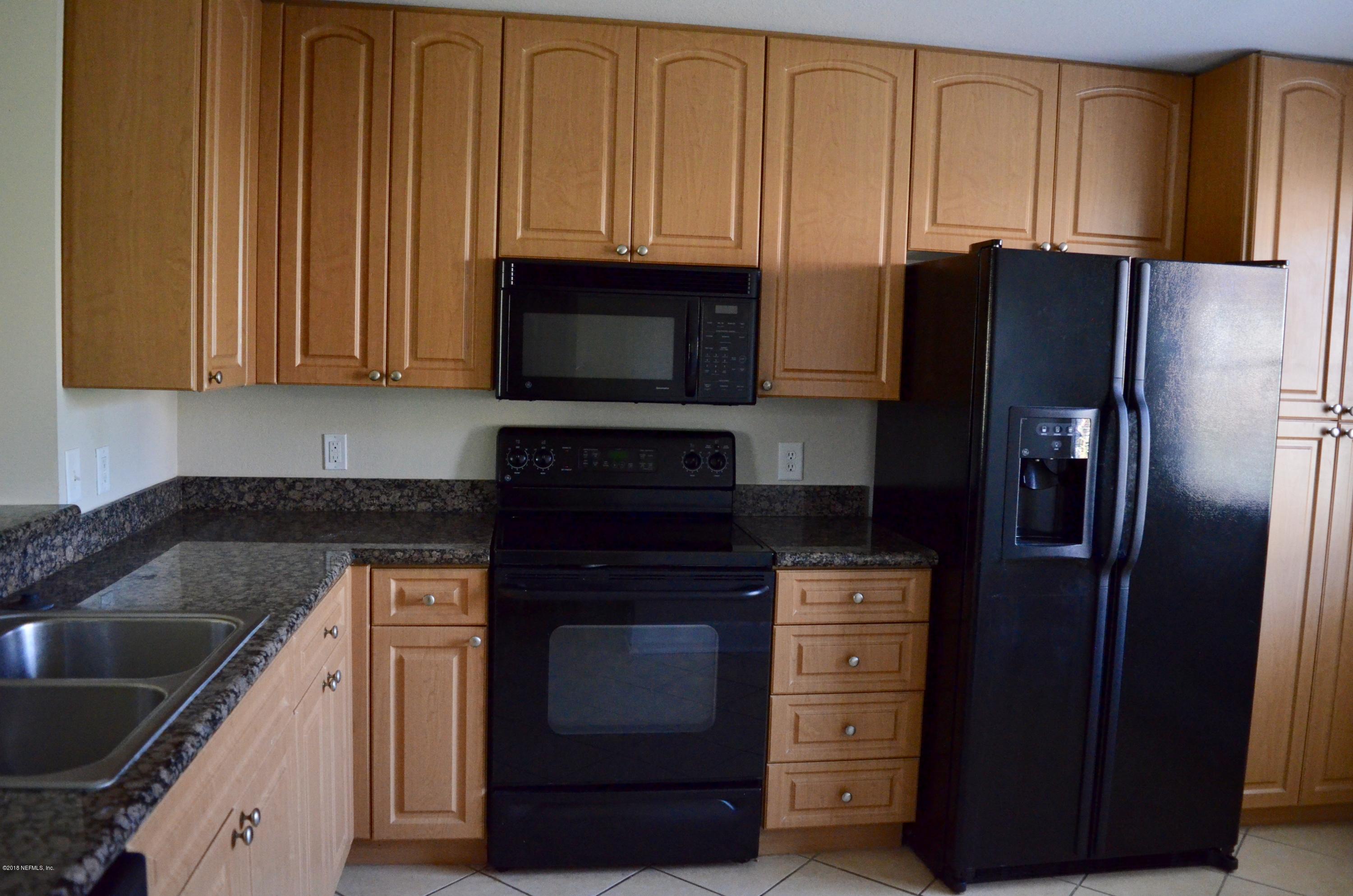 9745 Touchton Road, Unit 1821 Jacksonville, FL 32246 - Photo 8 of 33 a kitchen with granite countertop wooden cabinets and stainless steel appliances