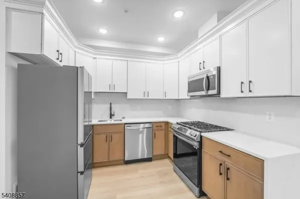 a kitchen with stainless steel appliances granite countertop white cabinets a sink a stove a refrigerator and white cabinets