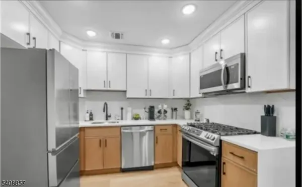 a kitchen with stainless steel appliances granite countertop white cabinets a sink a stove a refrigerator and white cabinets
