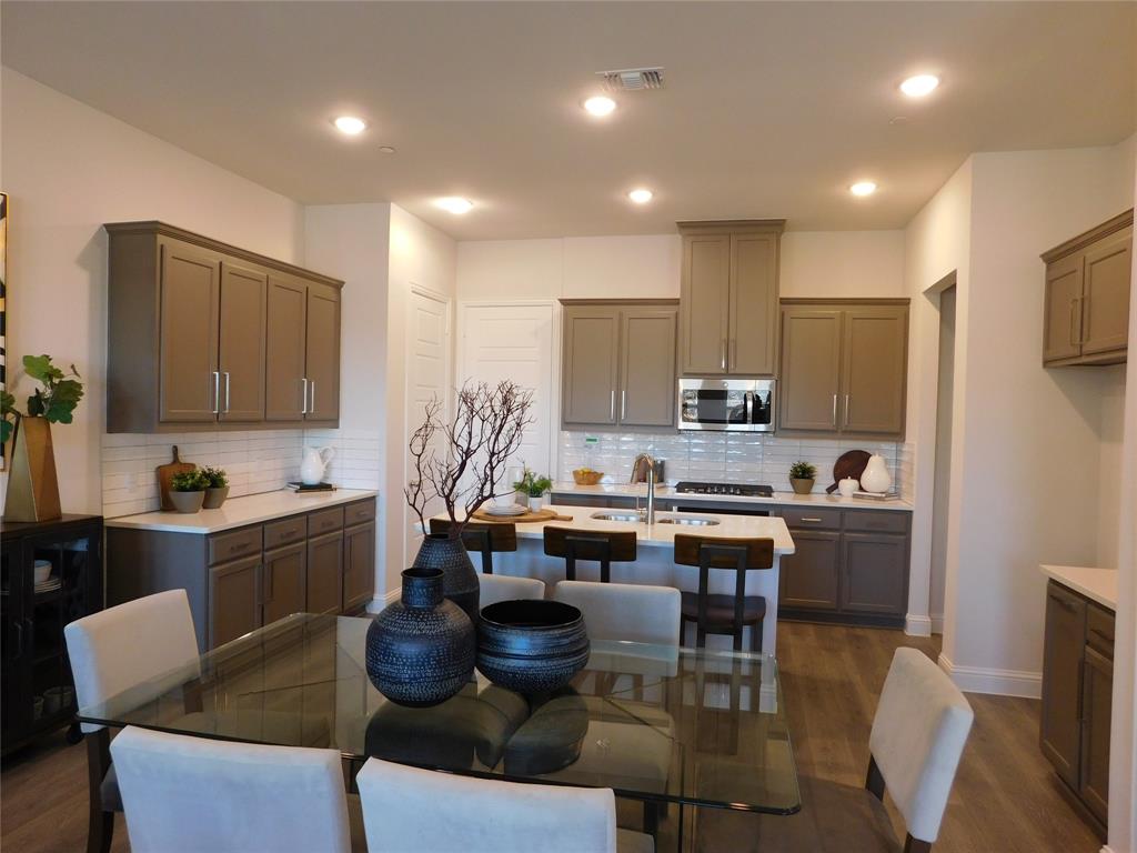 a kitchen with kitchen island granite countertop a table chairs stove a sink and dishwasher