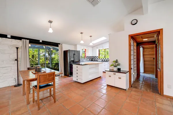 a kitchen with stainless steel appliances granite countertop a sink dishwasher a stove a dining table and chairs with wooden floor