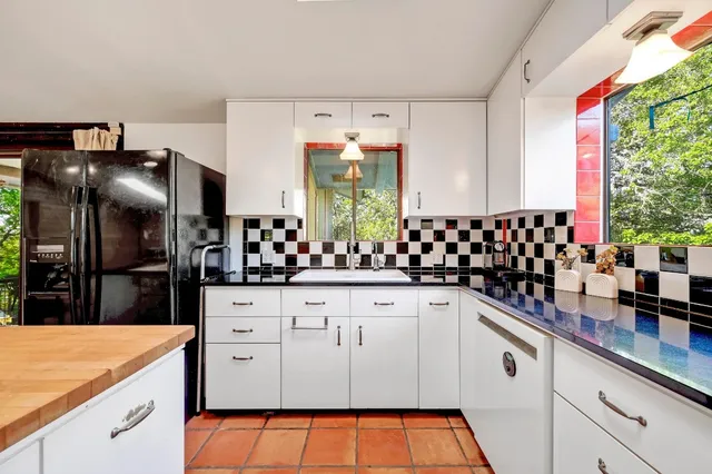 a kitchen with stainless steel appliances kitchen island granite countertop a refrigerator a sink dishwasher and white cabinets with wooden floor