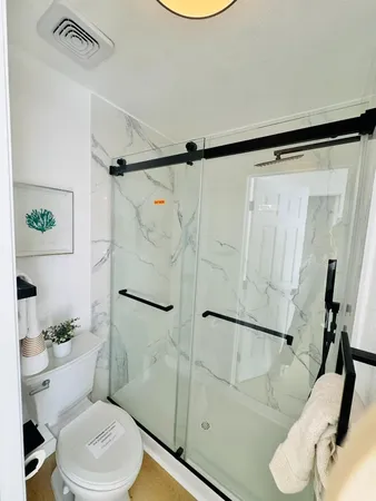 a white toilet sitting next to a bathroom sink and a shower