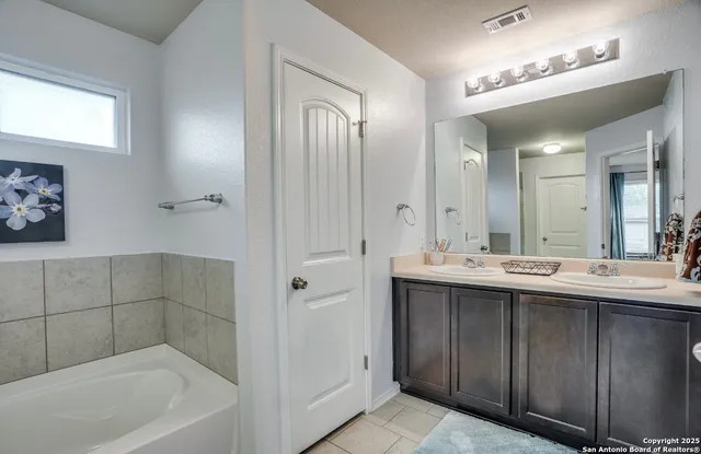 a bathroom with a tub a sink and mirror
