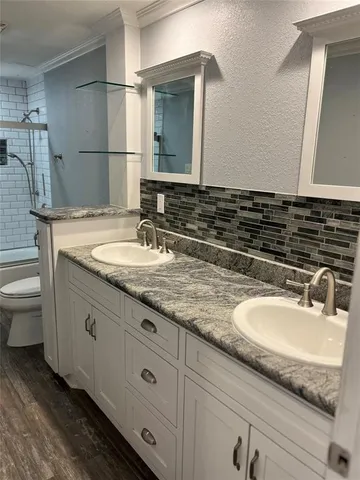 a bathroom with a granite countertop double vanity sink and a mirror