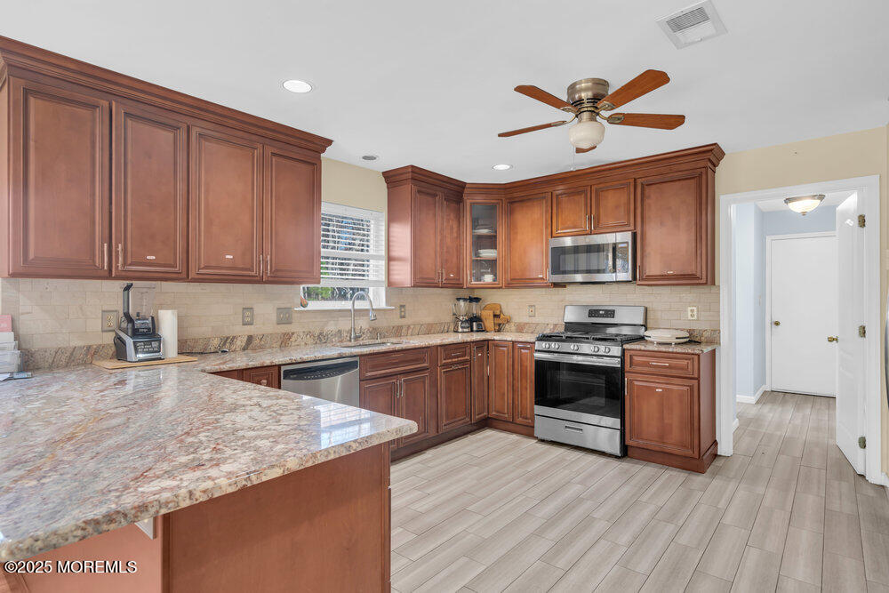 886 Green Valley Road Jackson, NJ 08527 - Photo 8 of 20 a kitchen with stainless steel appliances granite countertop hardwood floor sink stove and wooden cabinets