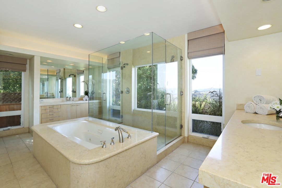 1629 Tower Grove Drive Beverly Hills, CA 90210 - Photo 22 of 29 a bathroom with a tub a sink and glass door