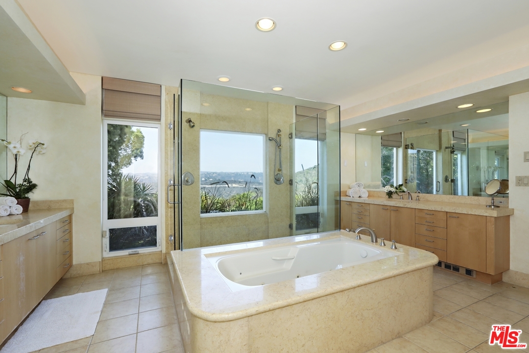1629 Tower Grove Drive Beverly Hills, CA 90210 - Photo 23 of 29 a bathroom with a tub a sink and a large mirror