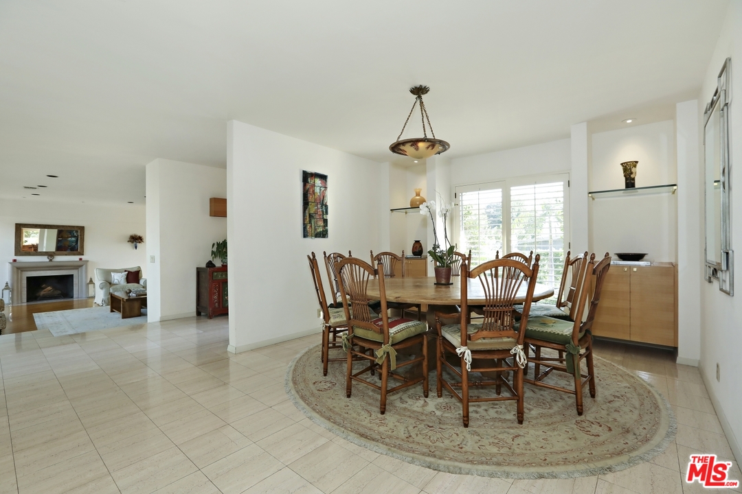 1629 Tower Grove Drive Beverly Hills, CA 90210 - Photo 9 of 29 a view of a dining room and livingroom with furniture wooden floor a rug a fireplace