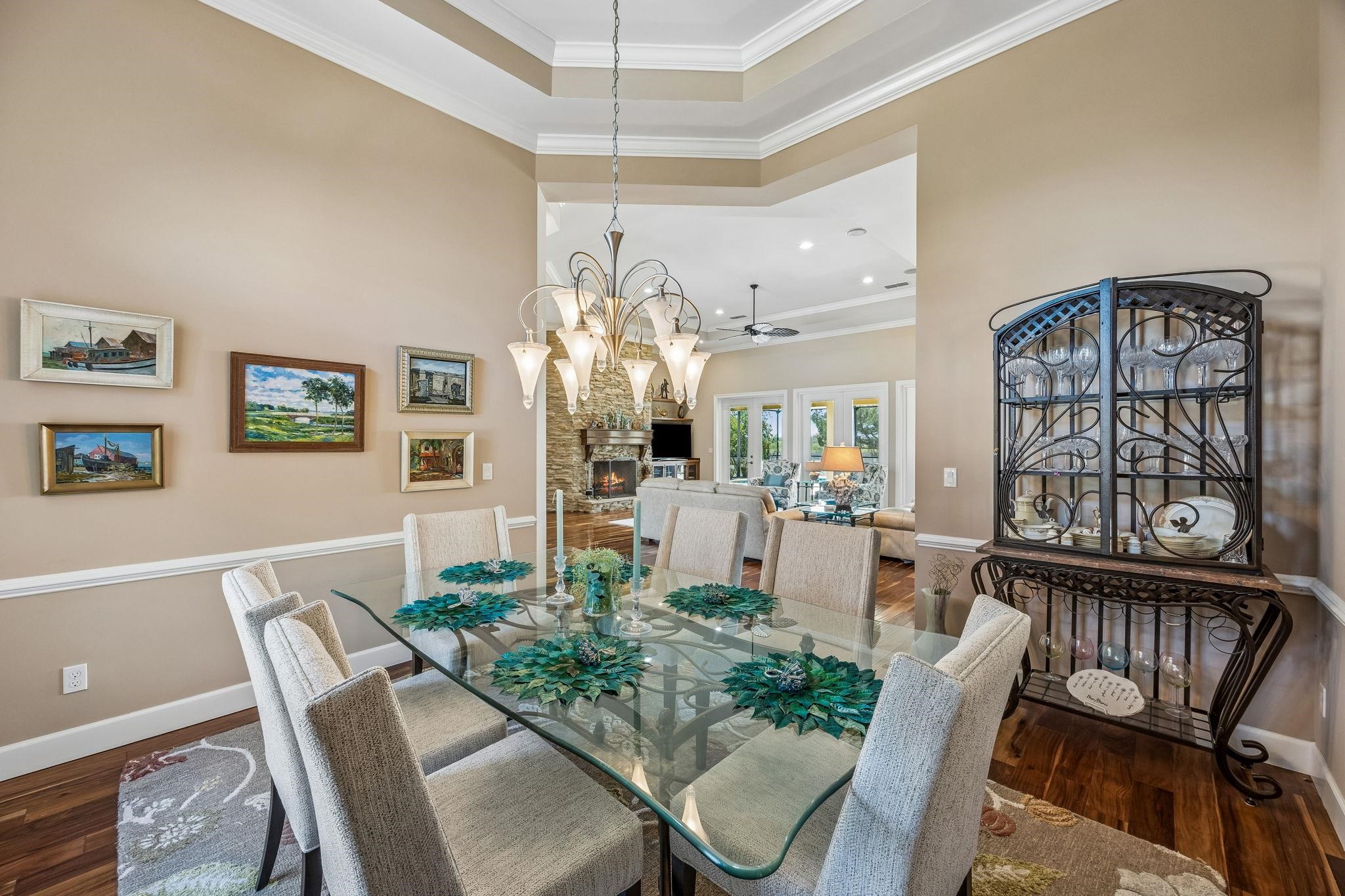 409 Lookout Point Drive St. Augustine, FL 32080 - Photo 14 of 90 Dining room with crown molding, dark wood finished floors, a fireplace, suspended lighting, and a ceiling fan