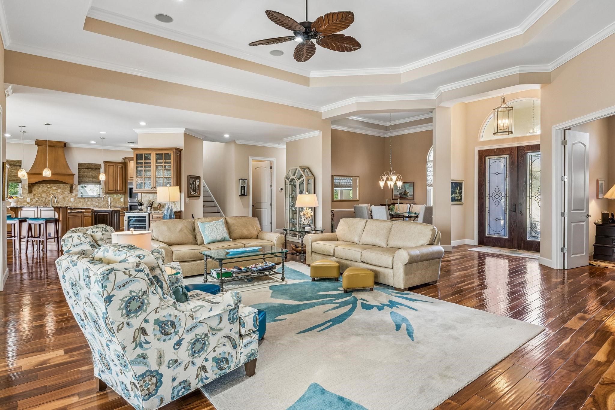 409 Lookout Point Drive St. Augustine, FL 32080 - Photo 15 of 90 Living room with a ceiling fan, a tray ceiling, dark wood-style flooring, a chandelier, and crown molding