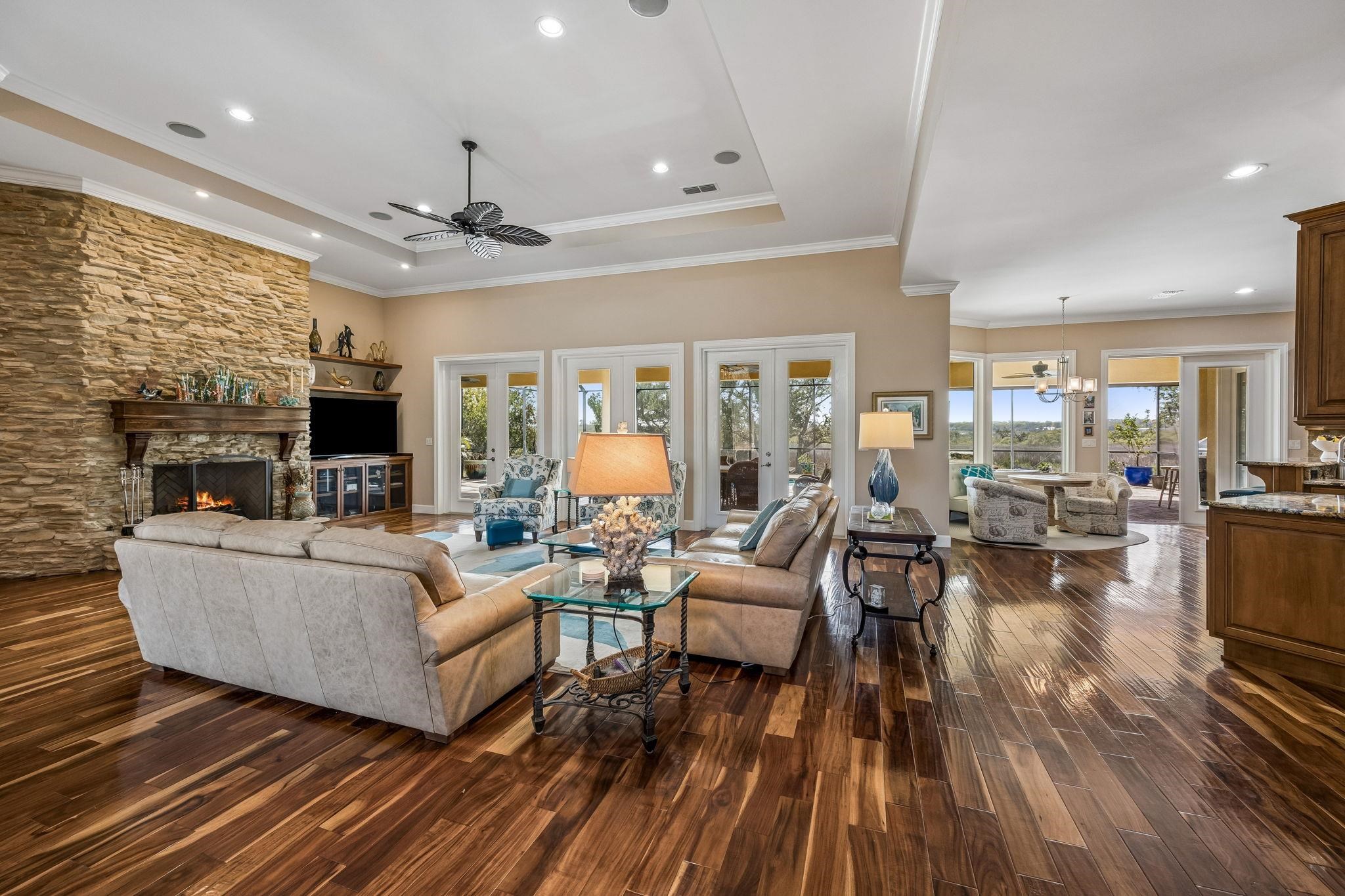 409 Lookout Point Drive St. Augustine, FL 32080 - Photo 20 of 90 Living area with dark wood-style floors, suspended lighting, a stone fireplace, ceiling fan, and a tray ceiling