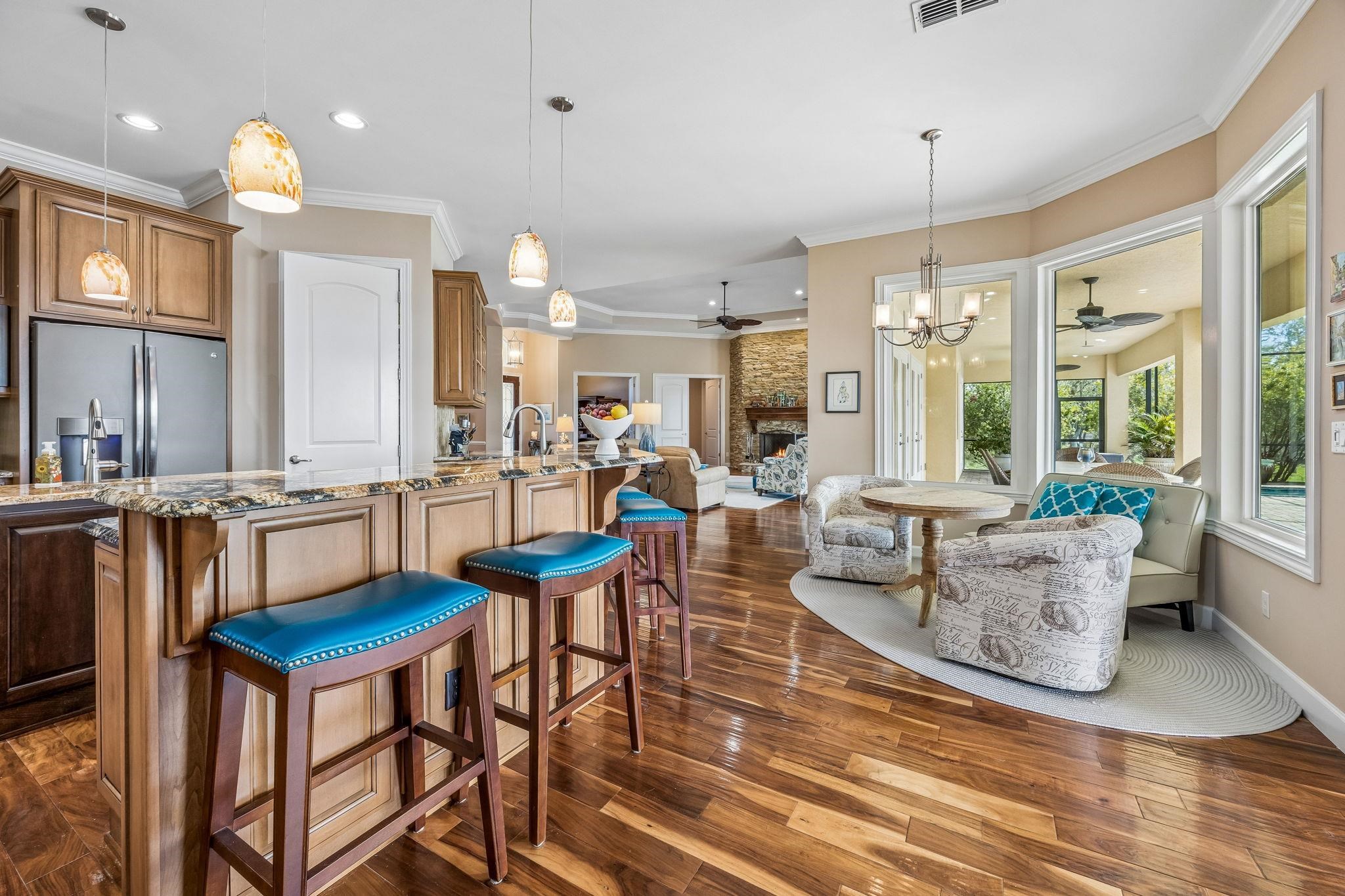 409 Lookout Point Drive St. Augustine, FL 32080 - Photo 89 of 90 Kitchen with a ceiling fan, open floor plan, suspended lighting, a stone fireplace, and light stone counters