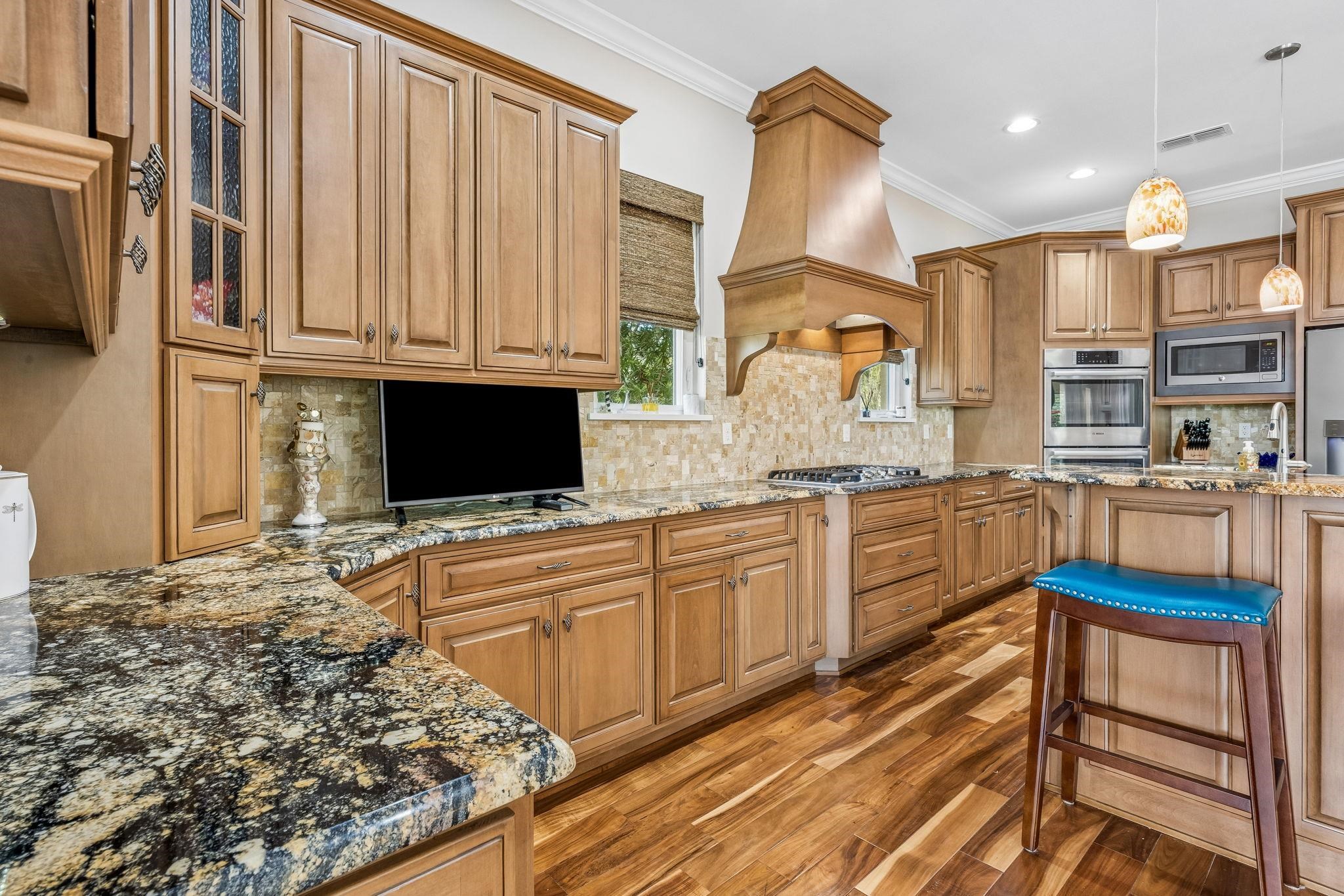 409 Lookout Point Drive St. Augustine, FL 32080 - Photo 24 of 90 Kitchen featuring dark stone countertops, wood finished floors, decorative backsplash, decorative light fixtures, and ornamental molding