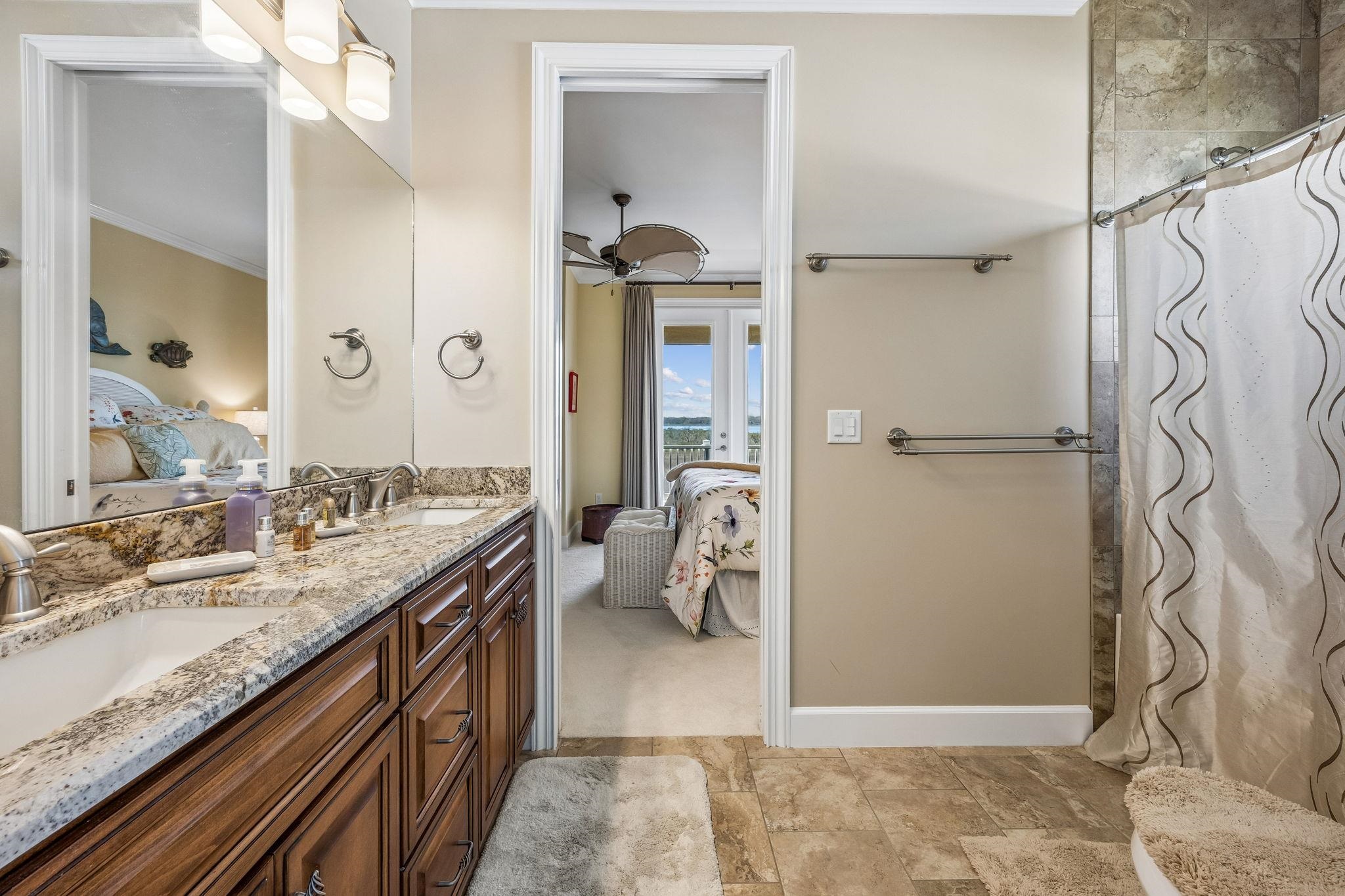 409 Lookout Point Drive St. Augustine, FL 32080 - Photo 71 of 90 Bathroom featuring connected bathroom, double vanity, a ceiling fan, and stone finish floors