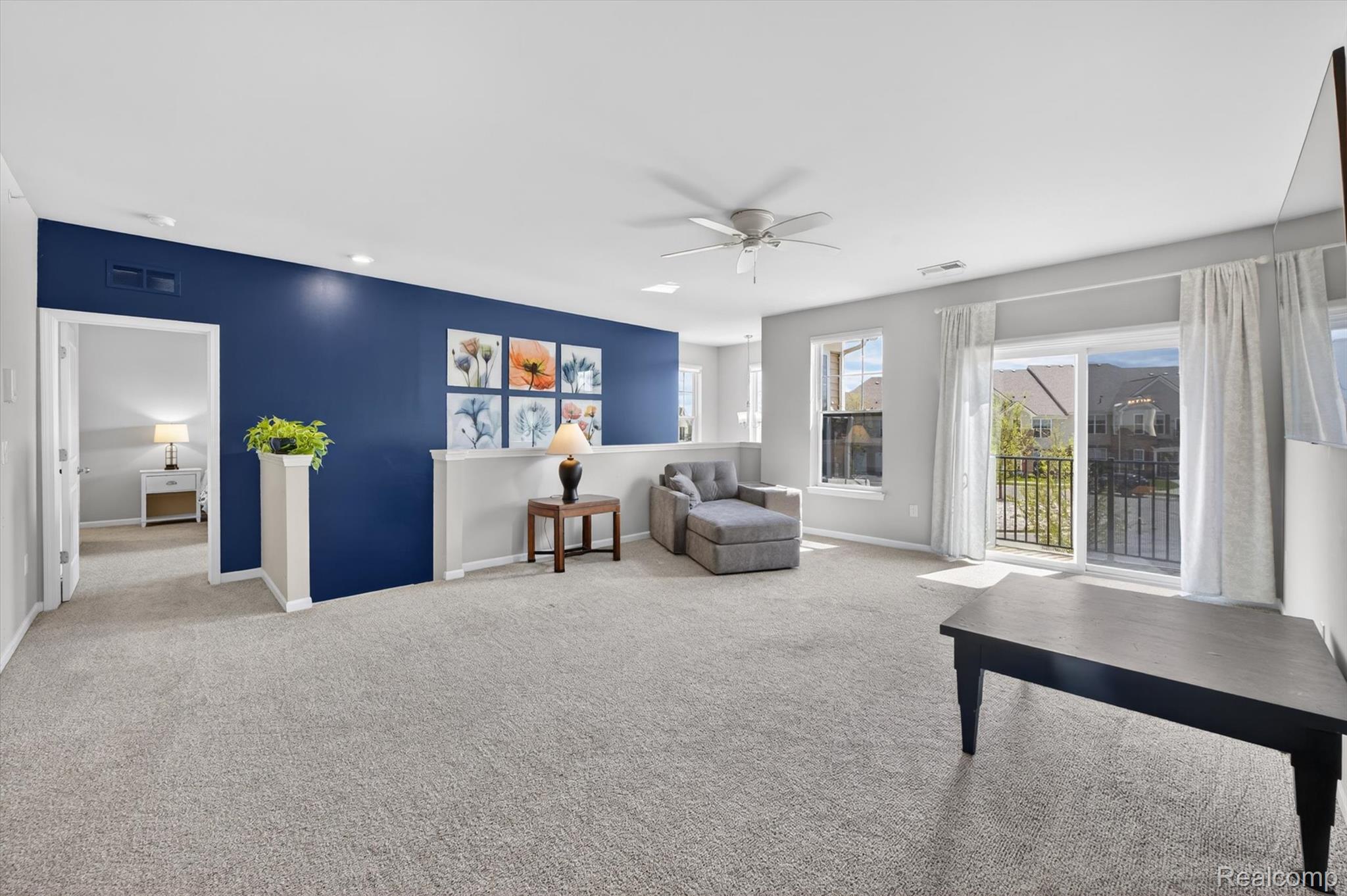 9789 Ridge Run Street Howell, MI 48855 - Photo 5 of 23 Open concept living area featuring large windows, balcony access, and bright airy finishes throughout.