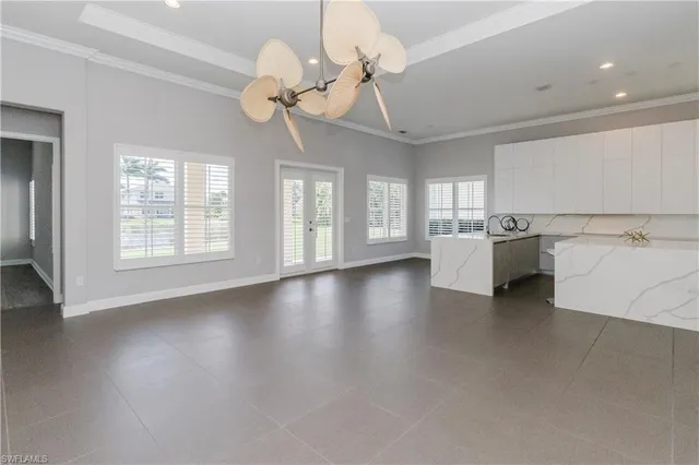 a view of a livingroom with a kitchen furniture a chandelier fan wooden floor and windows