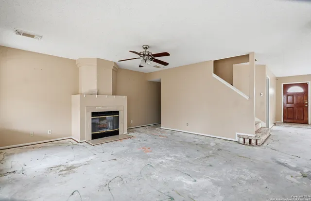 an empty room with fireplace and ceiling fan