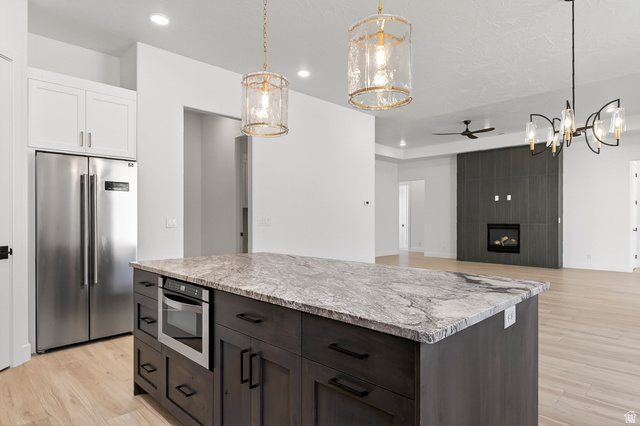 2862 South Mountain Rnch Road Cedar City, UT 84720 - Photo 14 of 64 Kitchen island featuring a stone countertop, built-in microwave, and dark wood-finish cabinetry with black hardware