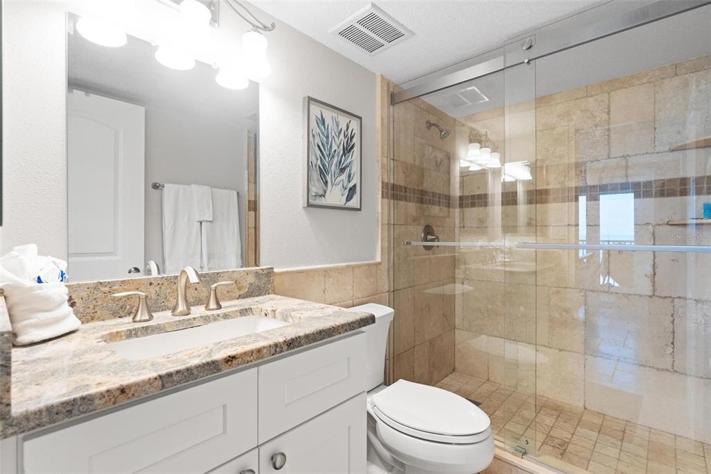 14900 Gulf Boulevard, Unit 202 Madeira Beach, FL 33708 - Photo 17 of 37 a bathroom with a granite countertop sink toilet a mirror and shower