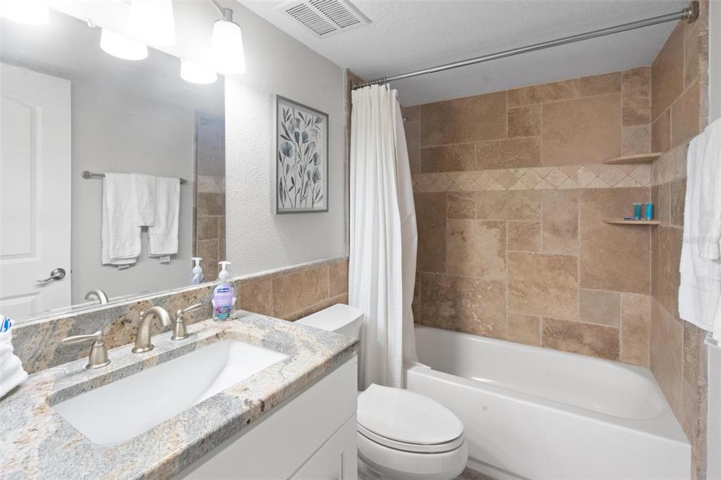 14900 Gulf Boulevard, Unit 202 Madeira Beach, FL 33708 - Photo 22 of 37 a bathroom with a granite countertop bathtub shower sink vanity mirror and toilet