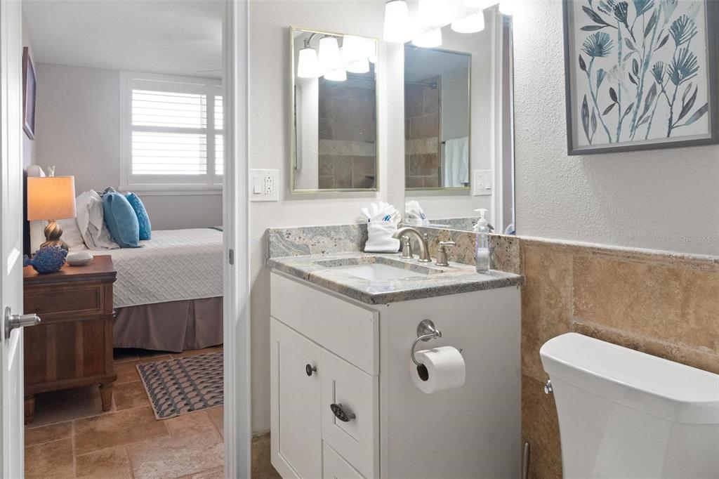 14900 Gulf Boulevard, Unit 202 Madeira Beach, FL 33708 - Photo 23 of 37 a bathroom with a sink vanity granite toilet and a mirror