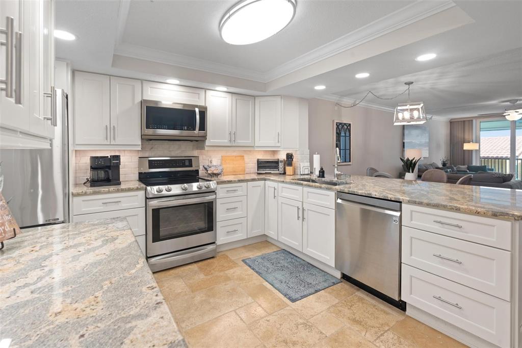 14900 Gulf Boulevard, Unit 202 Madeira Beach, FL 33708 - Photo 6 of 37 a kitchen with stainless steel appliances granite countertop a sink a stove top oven a counter space and cabinets