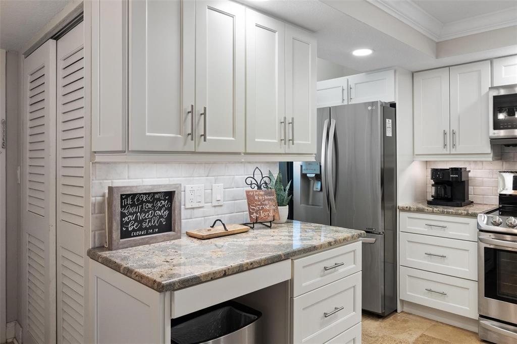 14900 Gulf Boulevard, Unit 202 Madeira Beach, FL 33708 - Photo 7 of 37 a kitchen with granite countertop a sink stainless steel appliances and white cabinets