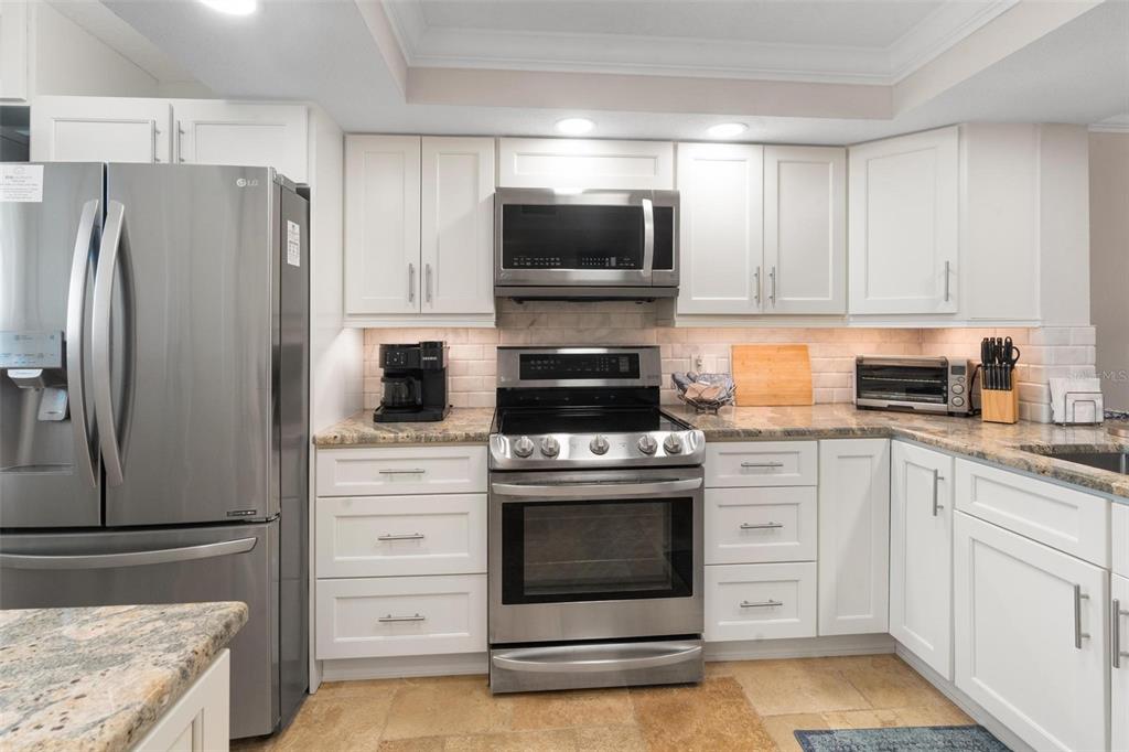 14900 Gulf Boulevard, Unit 202 Madeira Beach, FL 33708 - Photo 8 of 37 a kitchen with white cabinets and stainless steel appliances