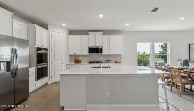 a kitchen with white cabinets sink and stove