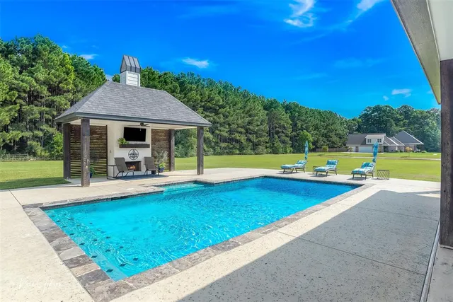 a view of swimming pool with seating area and trees in the background