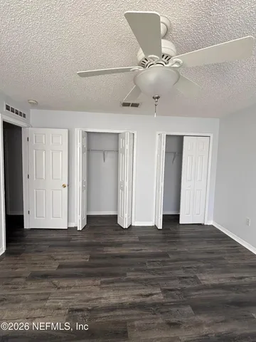 an empty room with wooden floor fan and windows