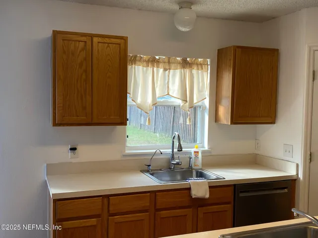 a view of an empty room with wooden floor and a chandelier
