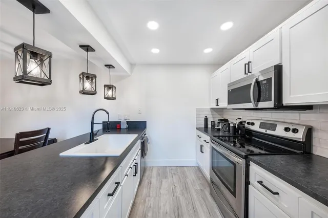 a kitchen with stainless steel appliances granite countertop a sink stove microwave and refrigerator