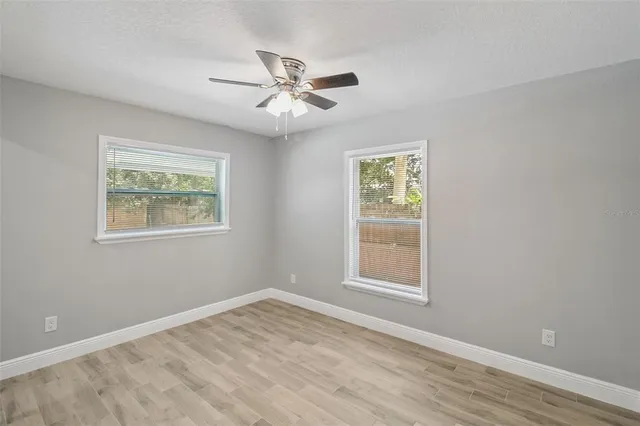 a view of an empty room with a window and wooden floor