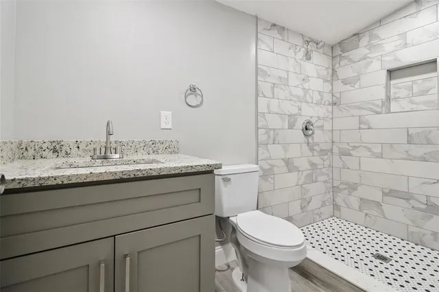 a bathroom with a granite countertop toilet a sink and a shower