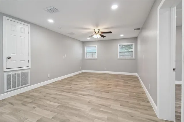 a view of empty room with wooden floor and fan