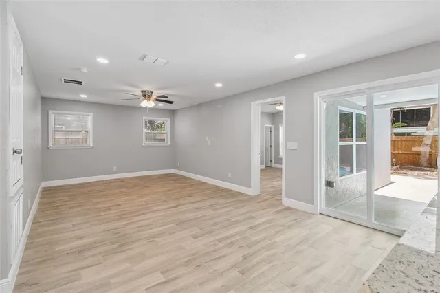 a view of empty room with wooden floor and fan