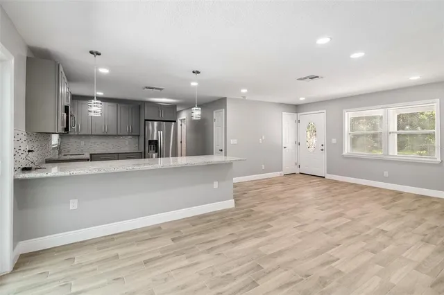 an open kitchen with kitchen island a sink wooden floor and a refrigerator