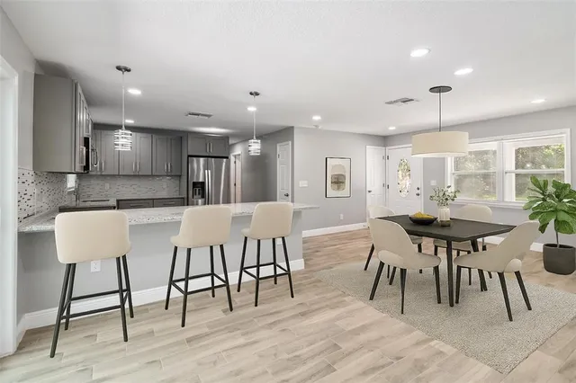 a kitchen with stainless steel appliances kitchen island granite countertop a dining table chairs and view living room
