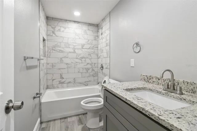 a bathroom with a granite countertop sink a toilet and bathtub