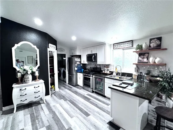 a kitchen with stainless steel appliances kitchen island granite countertop a stove a sink a dining table and chairs with wooden floor