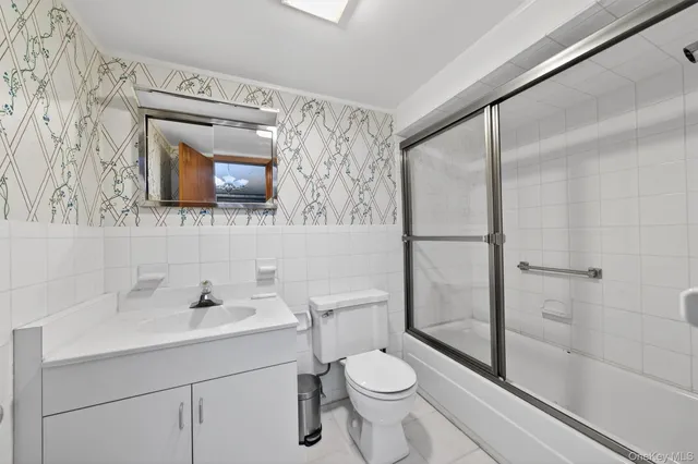 a bathroom with a toilet a sink a mirror a vanity and shower