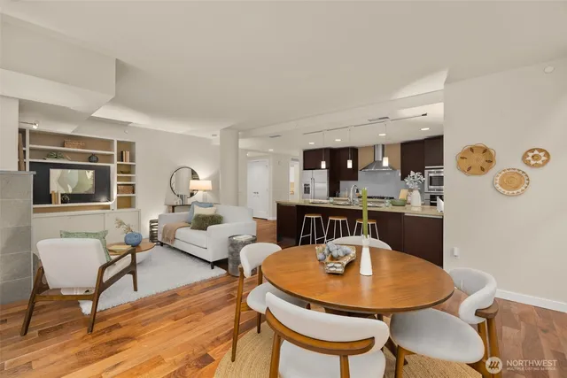 a living room with stainless steel appliances kitchen island a dining table and chairs with wooden floor