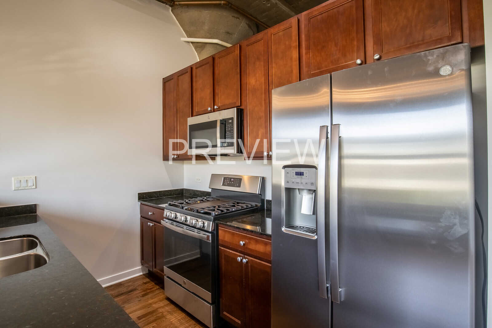 1071 West 15th Street, Unit 351 Chicago, IL 60608 - Photo 8 of 12 a kitchen with stainless steel appliances granite countertop a refrigerator a stove and a sink with wooden cabinets