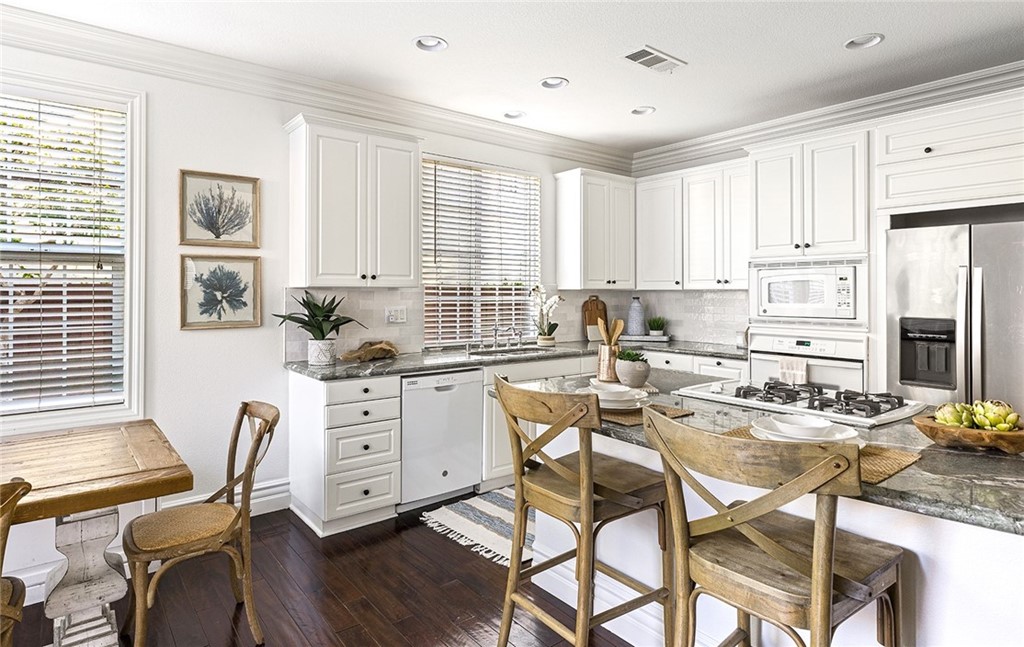 22 Alcott Street Ladera Ranch, CA 92694 - Photo 12 of 46 a kitchen with stainless steel appliances kitchen island granite countertop a stove a refrigerator a dining table and chairs with wooden floor